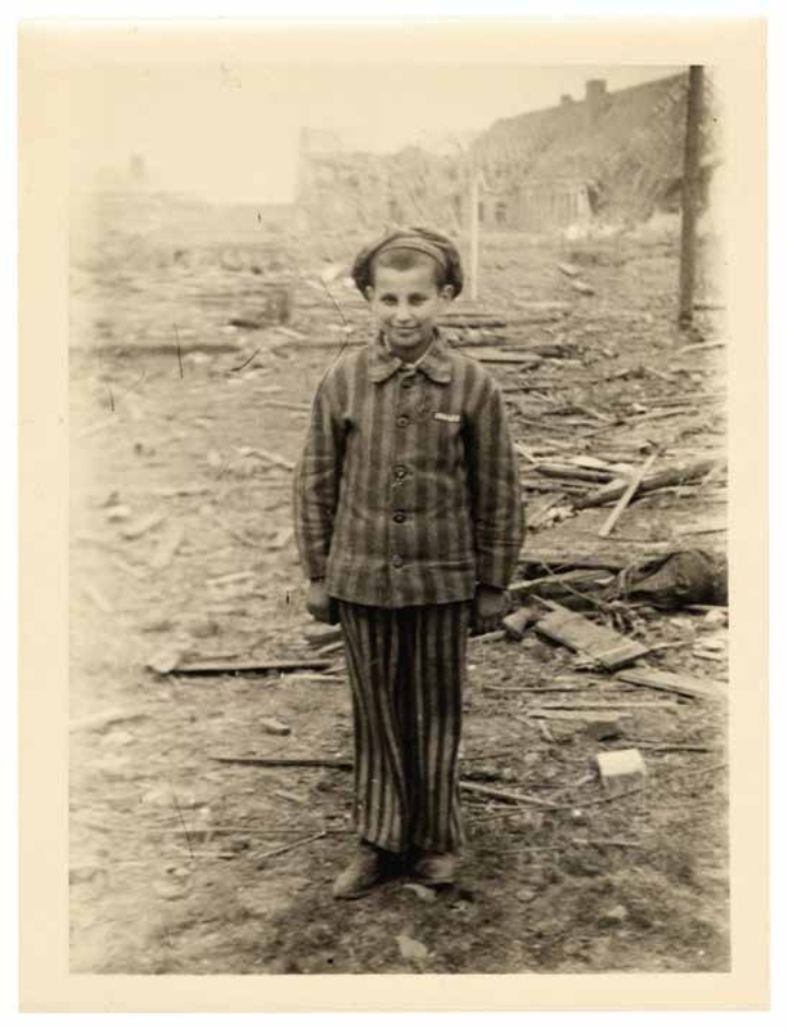 Ganzkörperbild eines Kindes vor dem zerstörten KZ