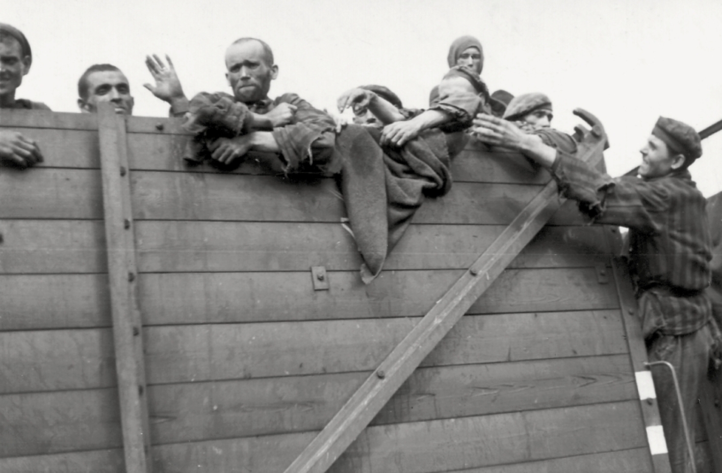 Schwarz-Weiß-Foto: Häftlinge schauen über den Wagenrand eines Güterwaggons