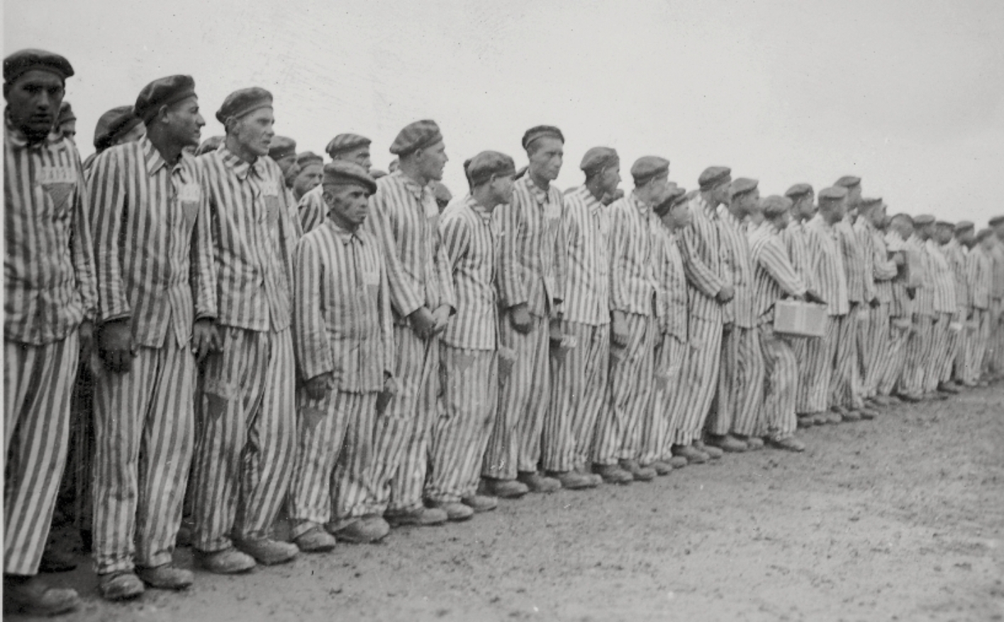 Schwarz-Weiß-Foto von Häftlingen, die nebeneinander aufgereiht auf dem Appellplatz stehen