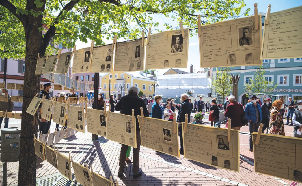 Fotografie der Gedenkveranstaltung auf Schrannenplatz in Erding, im Vordergrund Installation der Arbeitskarten, im Hintergrund Besucher:innen der Veranstaltung