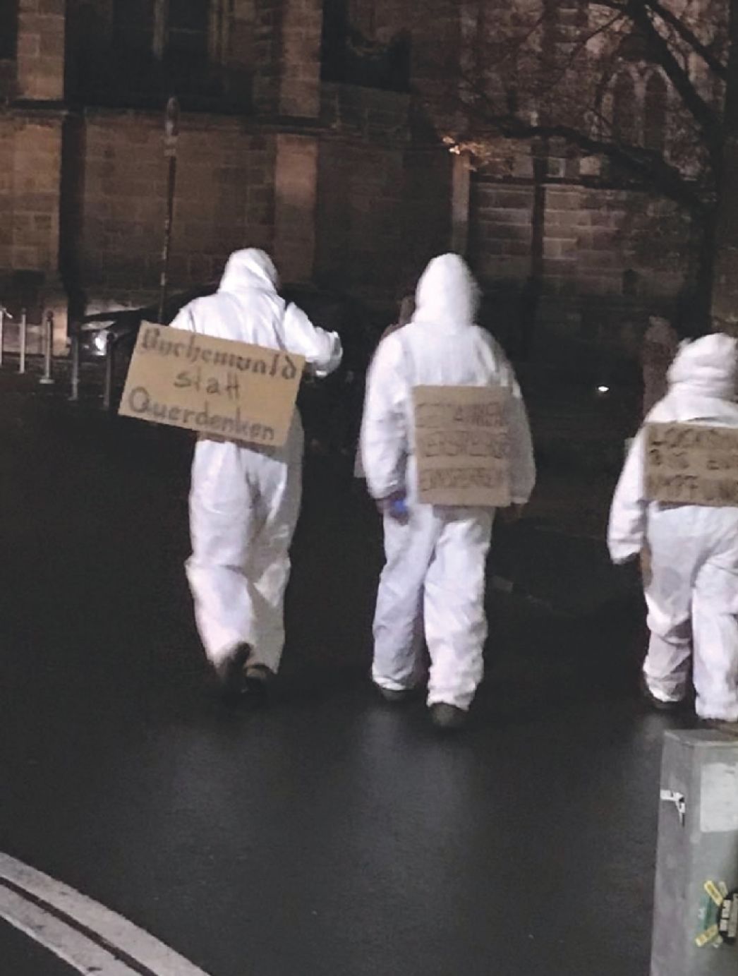 Querdenken-Aktivisten in Maleranzügen mit Plakaten: "Buchenwald statt Querdenken"