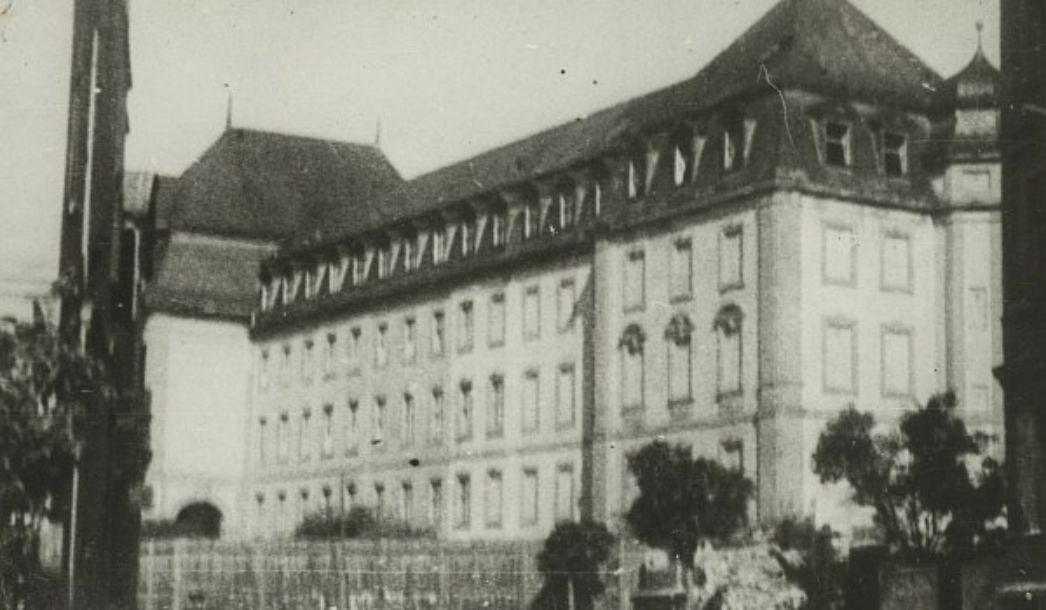 Blurred image of a large, four-story city building. 