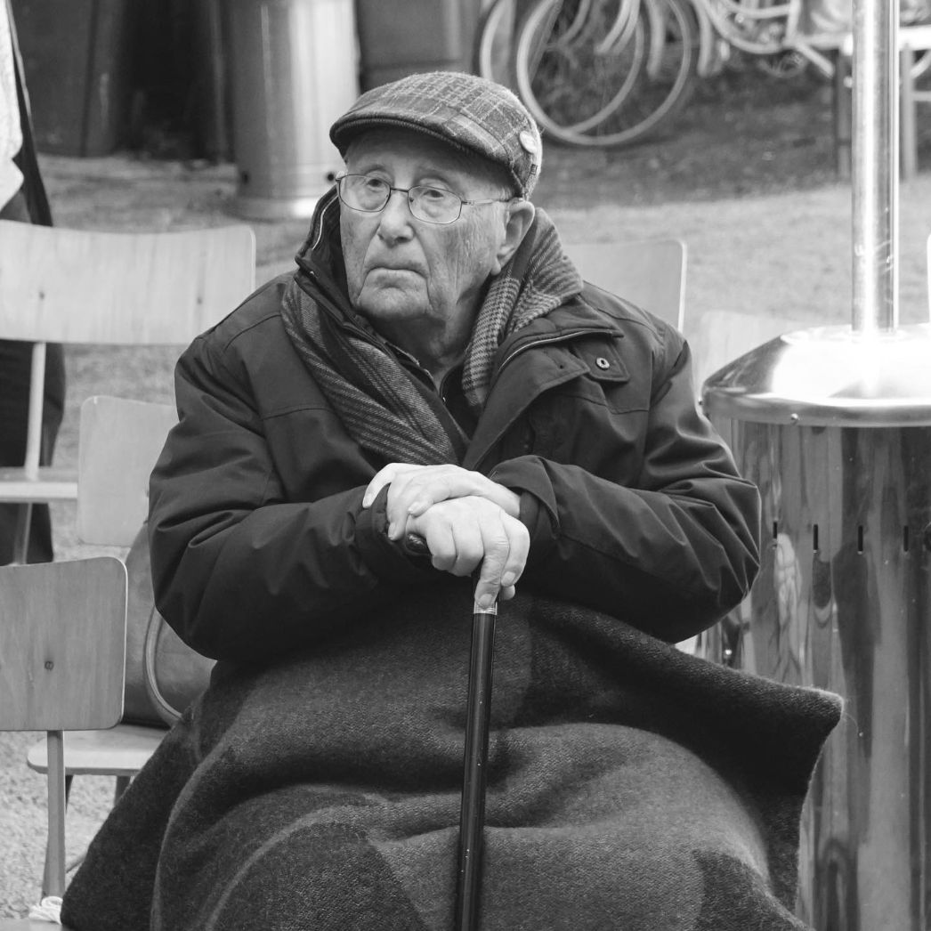 Albrecht Weinberg sitzt auf einem Stuhl und stützt sicht auf einen Gestock.