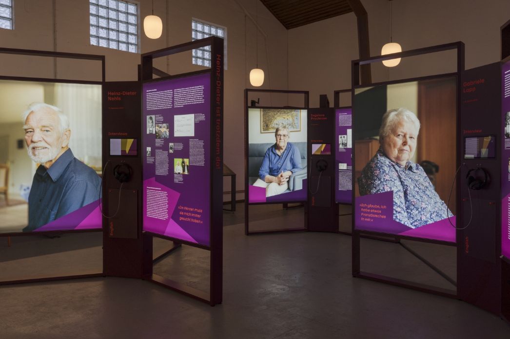 Ausstellungsansicht mit großen Portraitfotos und Informationstafeln mit Text