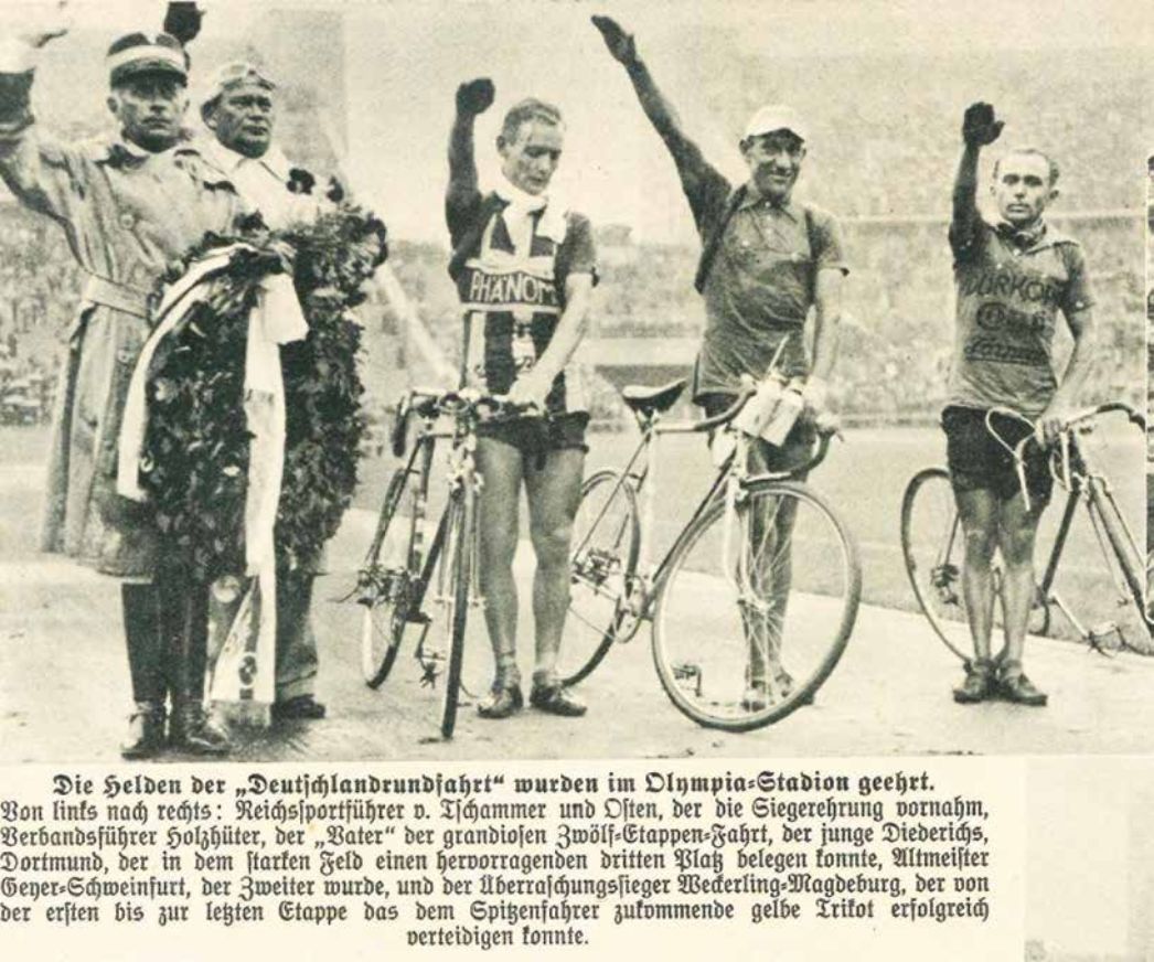 Zeitungsausschnitt: Foto von drei Radfahrern, die den Hitlergruß zeigen; links der Reichssportführer, der den Kranz zur Ehrung hält
