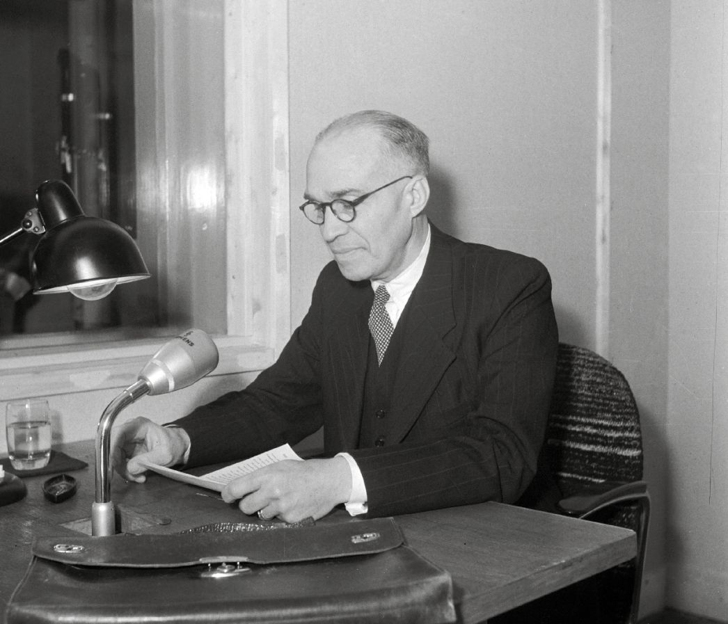 Schwarz-Weiß-Foto: Johann Logemann vor einem Mikrofon sitzend