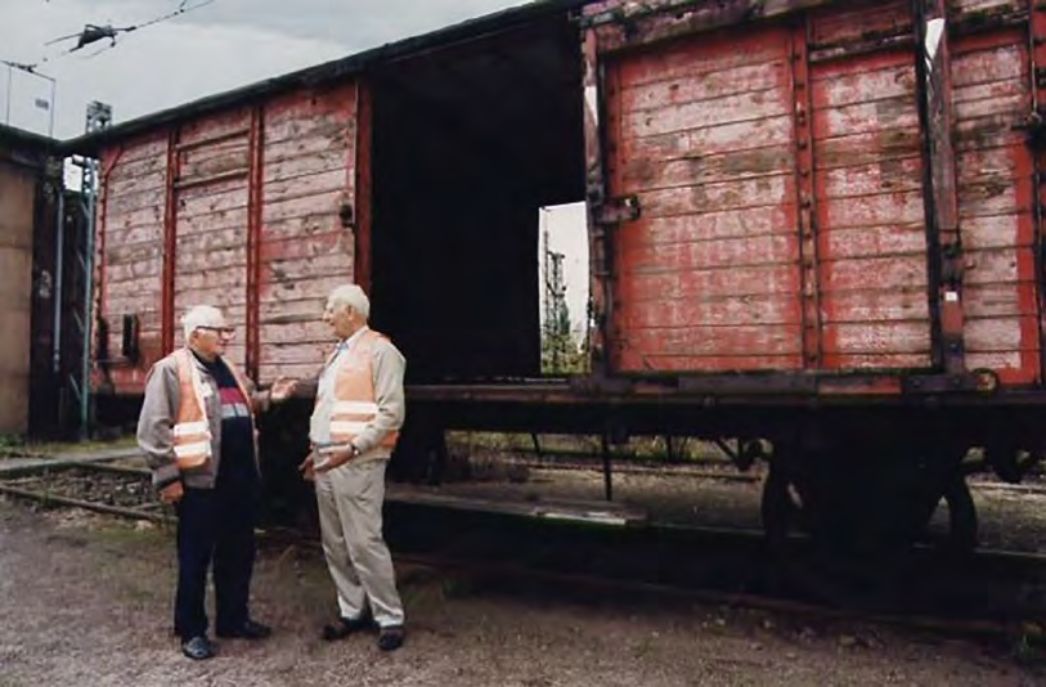 Zwei ältere Männer (Werenitsch und Agafonow) vor einem Zug im Rahmen eines Besuchsprogramms für ehemalige Zwangsarbeiter.