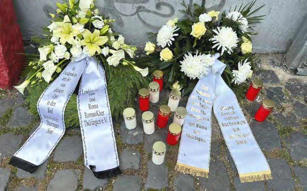 Zwei Kränze und Kerzen zum Gedenken an die ermordeten Sinti und Roma.
