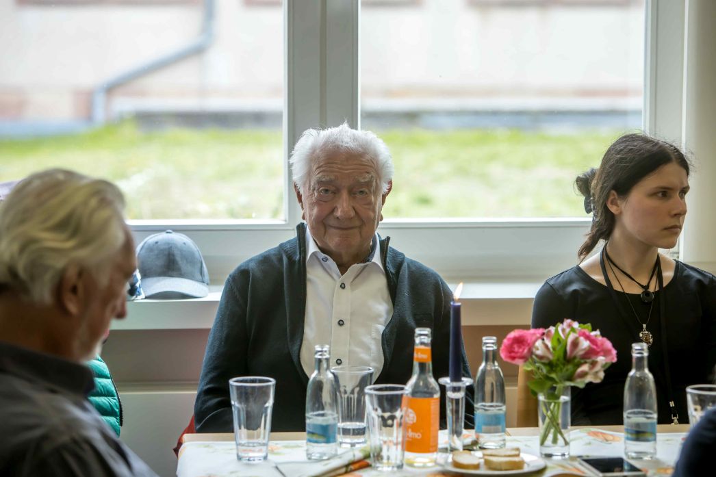 Dieses Foto zeigt den Speziallager-Überlebenden Peter Hansen bei einer Begegnung mit jüngeren Menschen – sehr wahrscheinlich im Rahmen der Tage der Begegnung in der Gedenkstätte Buchenwald. Die Atmosphäre ist ruhig und würdevoll, das Setting wirkt wie ein Gesprächs- oder Begegnungstisch zwischen Generationen.