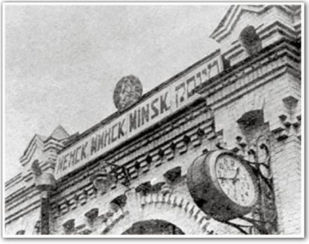 Das Bild zeigt den historischen Bahnhof von Minsk (Минск), wie er in einer alten Fotografie abgebildet ist. Auffällig ist die mehrsprachige Beschriftung über dem Eingang: Links auf Russisch: „Минск“ In der Mitte auf Lateinischer Schrift: „MINSK“ Rechts auf Hebräisch: „מינסק“ Zusätzlich ist eine große Bahnhofsuhr gut sichtbar, ein klassisches Symbol für Bahnhofsgebäude. Der Baustil mit Rundbogen und Ziegelornamentik lässt auf das späte 19. oder frühe 20. Jahrhundert schließen.