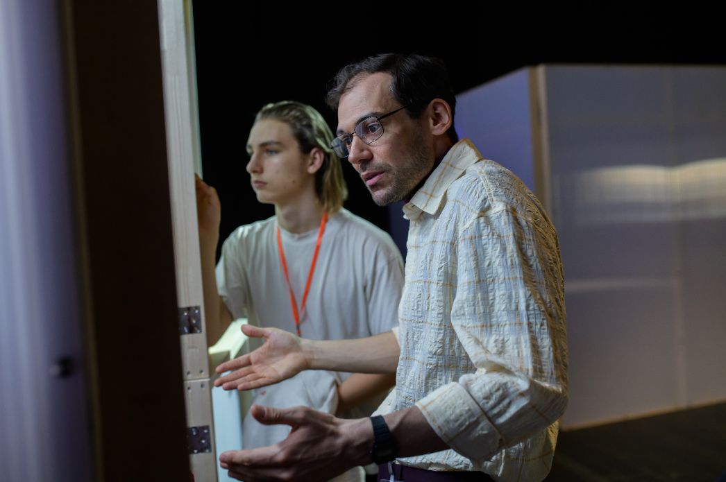 Zwei Personen stehen vor einem Ausstellungsmodul und tauschen sich intensiv darüber aus. Eine Person erklärt gestikulierend Details, während die andere aufmerksam zuhört und auf das Objekt blickt.