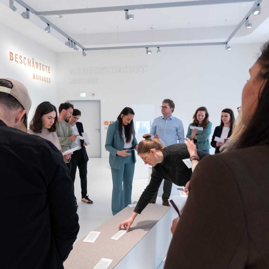 Eine Gruppe arbeitet gemeinsam an Textkarten in der Ausstellung. Auf der Wand im Hintergrund steht "Beschädigte".