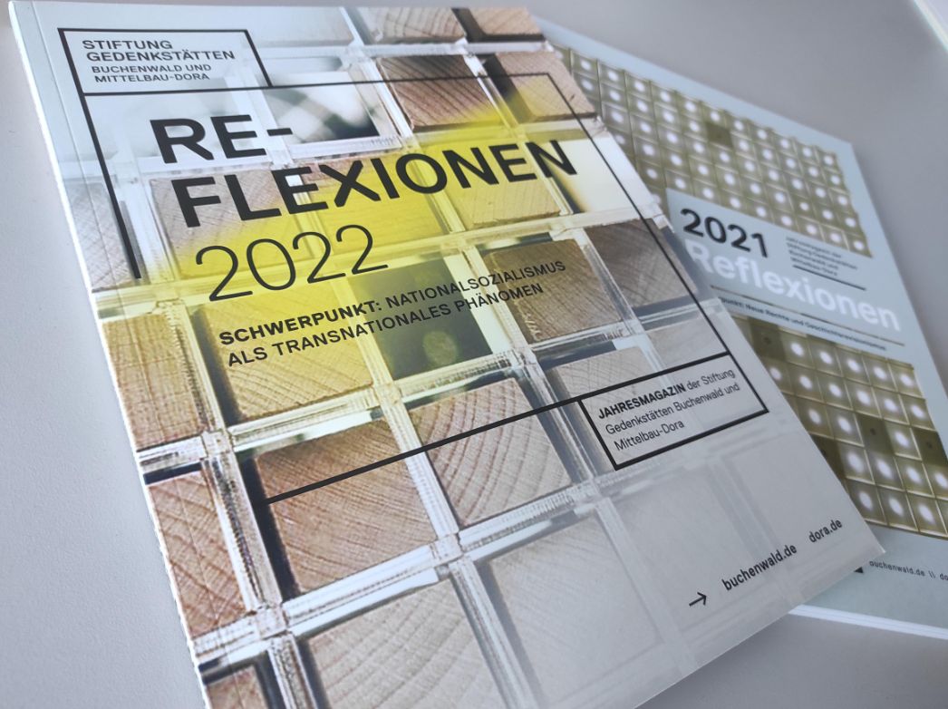 The 2012 and 2021 issues of "Relexionen" magazine on one table. the 2022 issue is partially on top of the 2021 version