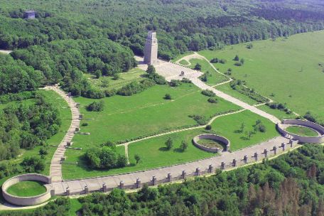 Aerial view of the memorial site. At the top left, the path begins downhill. Further down, the balcony-like Street of Nations stretches from one ring grave to the next. Halfway down, another ring grave. From there uphill the path leads to the bell tower.