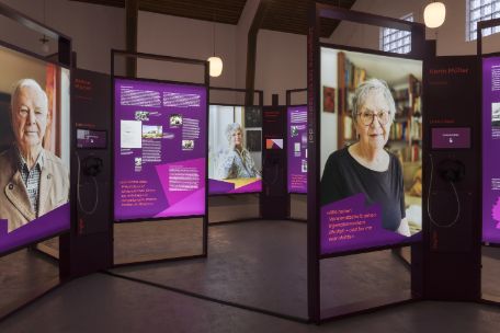 Ausstellungsansicht mit großen Portraitfotos und Informationstafeln mit Text