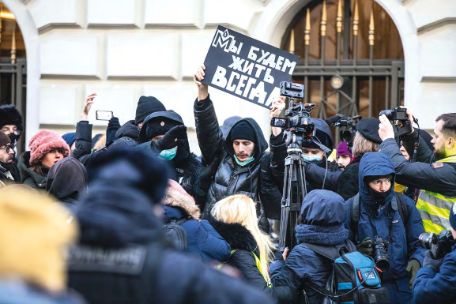 Aktivist, der Protestschild hochhält, umringt von vielen Leuten vor dem Obersten Gerichtsof in Moskau