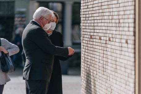 Das Foto zeigt Bundespräsident Frank-Walter Steinmeier vor der Kunstinstallation „Verschwindende Wand“, eine ca. zwei Meter hohe und fünf Meter breite Holzwand, deren Inneres sich aus Holzklötzchen zusammensetzt.