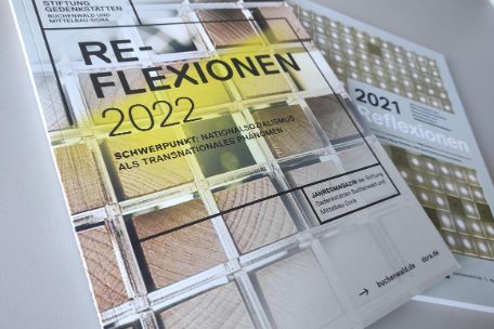 Die Ausgaben des "Relexionen"-Magazin von 2012 und 2021 auf einem Tisch. die Ausgabe von 2022 liegt teilweise über der Version von 2021
