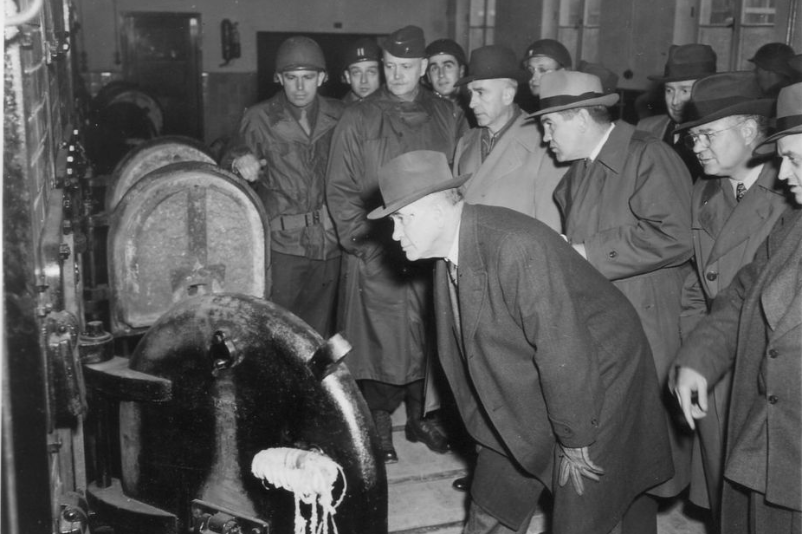 Amerikanische Kongressabgeordnete besichtigen das Krematorium. Senator Alben W. Barkley schaut in einen der Krematoriumsöfen.