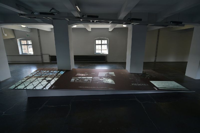 First floor of the exhibition. At the beginning of the concentration camp exhibition, on the first floor, there is a slightly slanted panel onto which an audio-visual video collage is projected. Otherwise, the room is empty.
